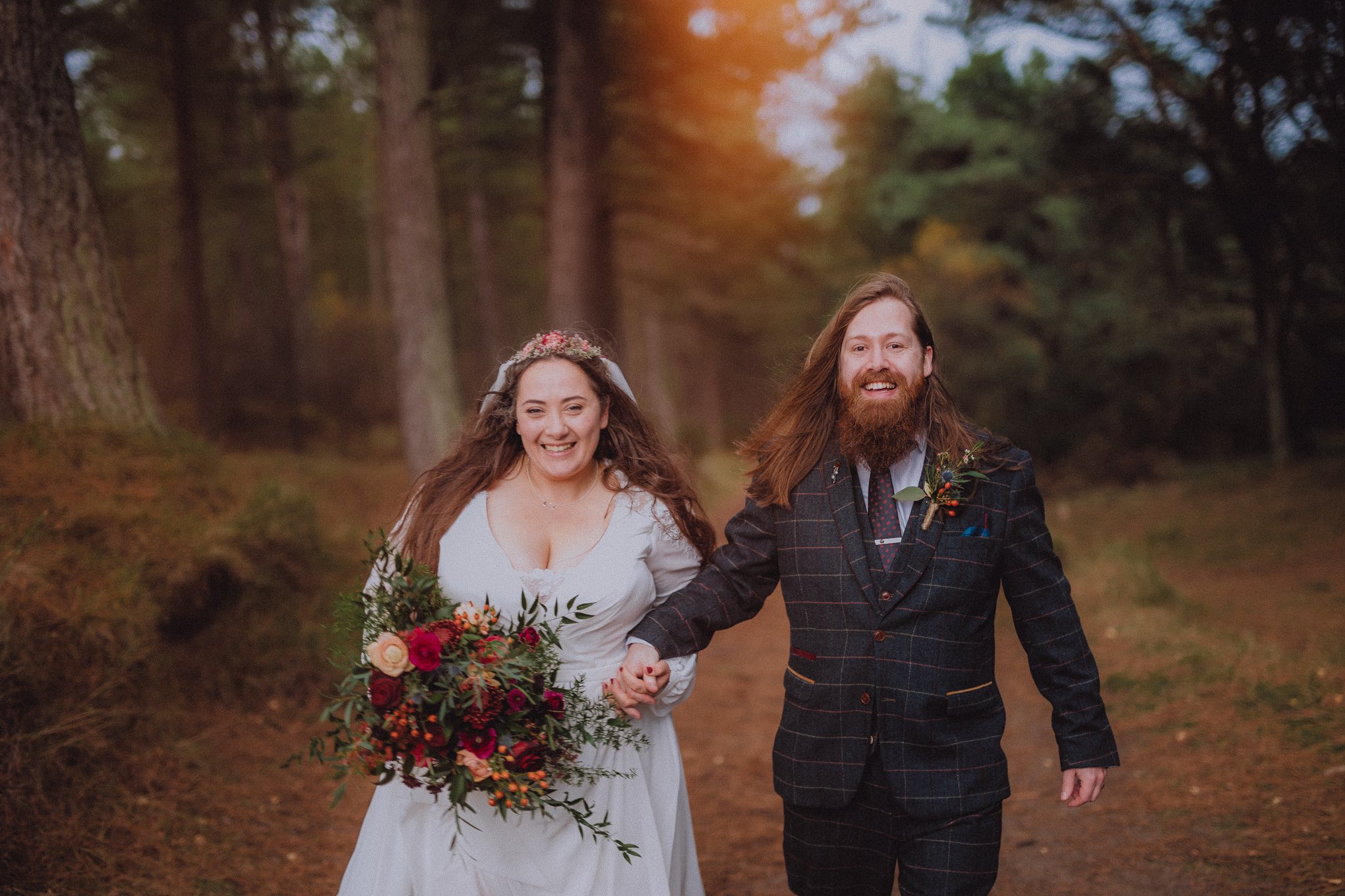 Bride and groom walking hand in hand through woodland just after their ceremony, smiling freely with natural movement and emotion, relax natural wedding photographer Glasgow Scotland