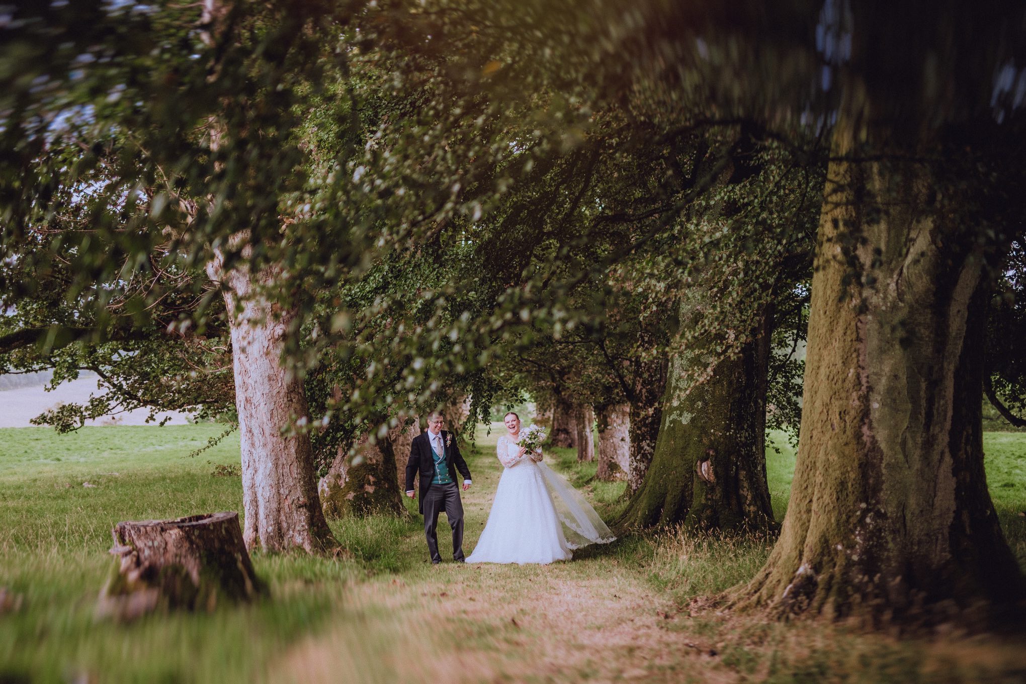 A peaceful, intimate moment of a couple walking through woodland on their wedding day. Relaxed waiting for photography in Scotland, captured with a documentary wedding photography style that values atmosphere and authenticity