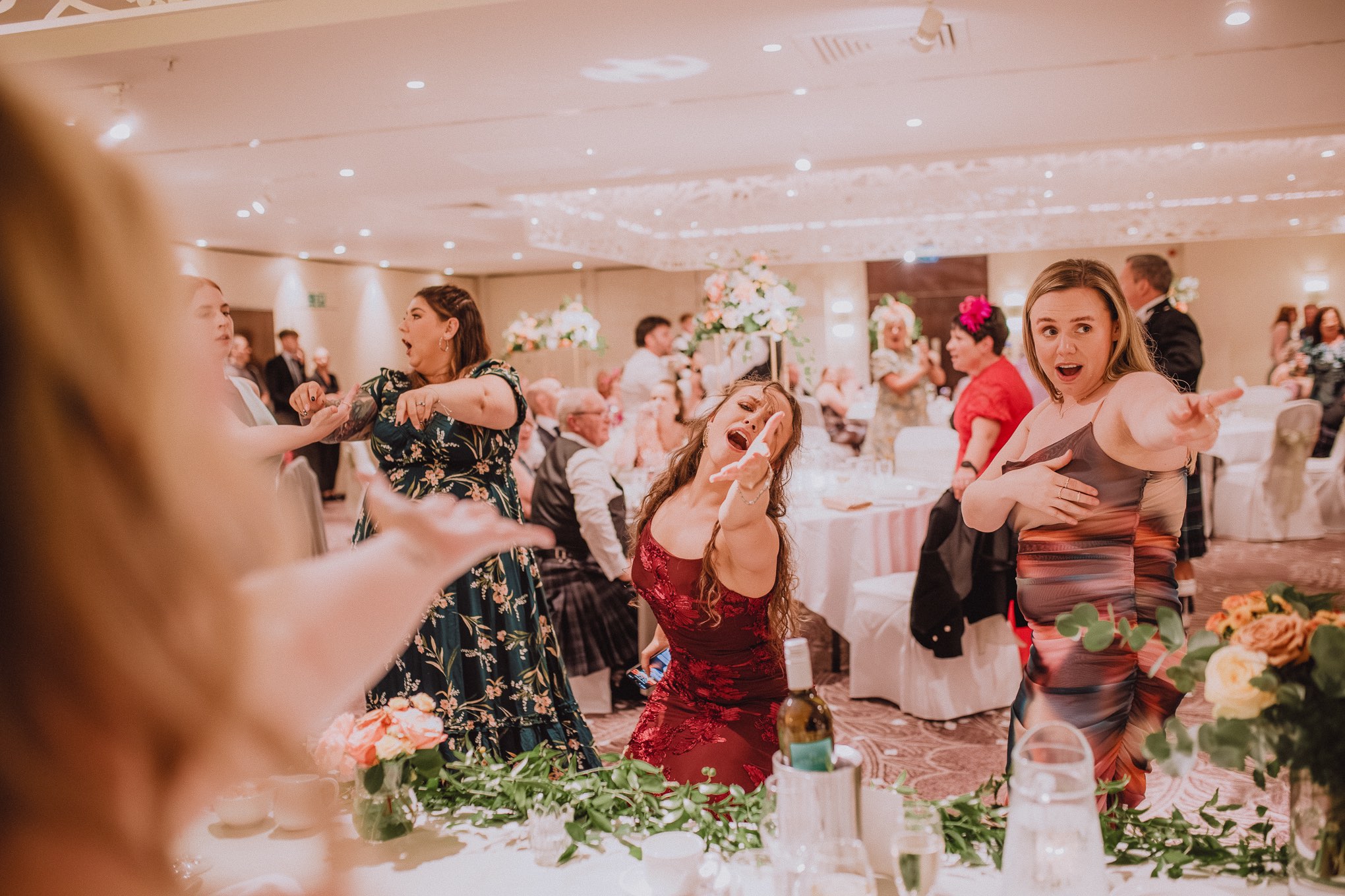 Wedding guest dancing wildly on the dance floor during the evening reception, arms raised under colourful party lights and blurred motion, relax natural wedding photographer Glasgow Scotland