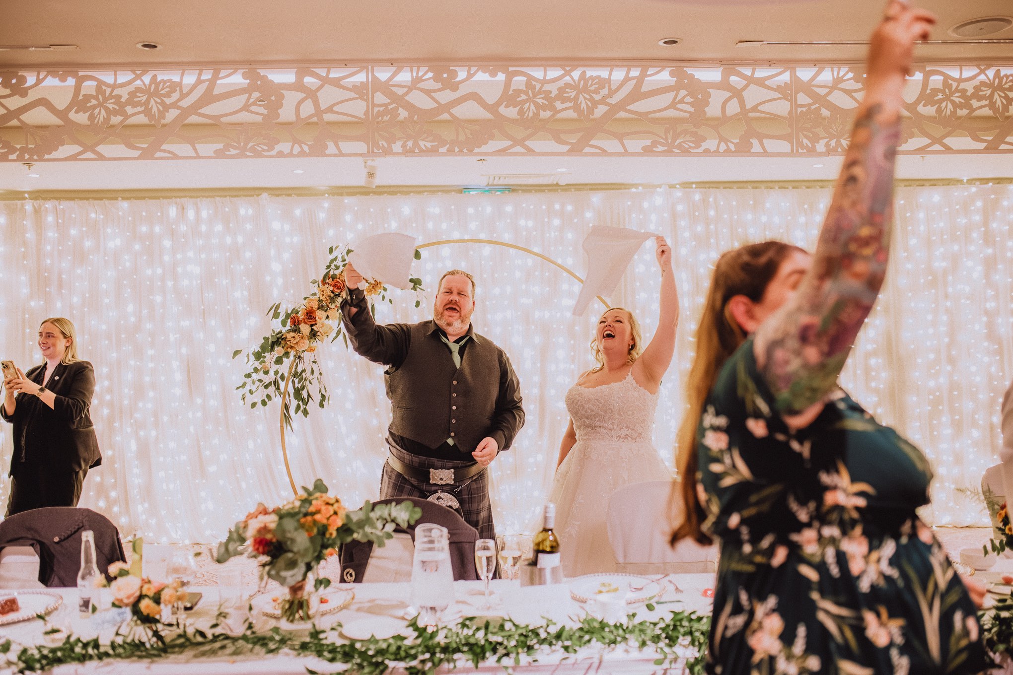 Wedding guest dancing wildly on the dance floor during the evening reception, arms raised under colourful party lights and blurred motion, relax natural wedding photographer Glasgow Scotland