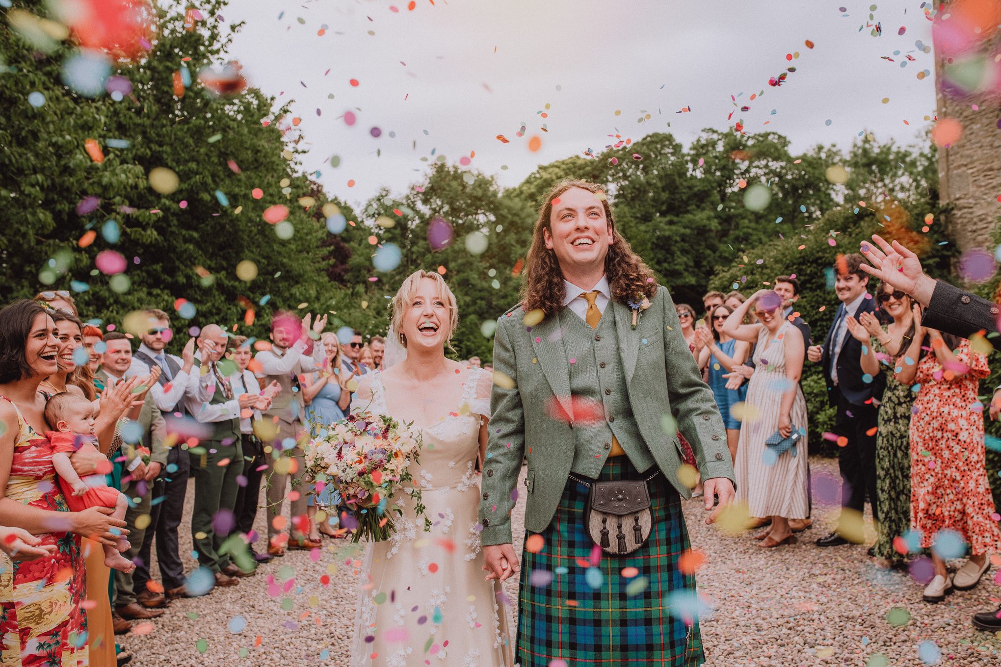 A candid confetti walk at a Scottish wedding, capturing genuine laughter, movement, and emotion. Relaxed waiting for photography in Scotland with a documentary approach focused on real moments and natural storytelling